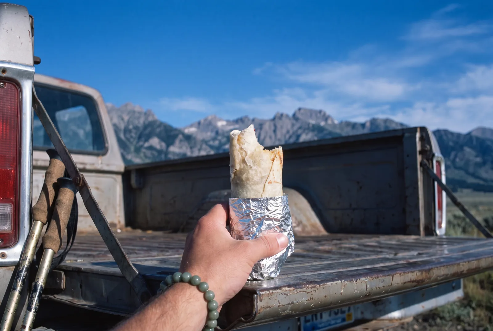 A wrapped breakfast burrito held in hand at a Montana trailhead before a hike