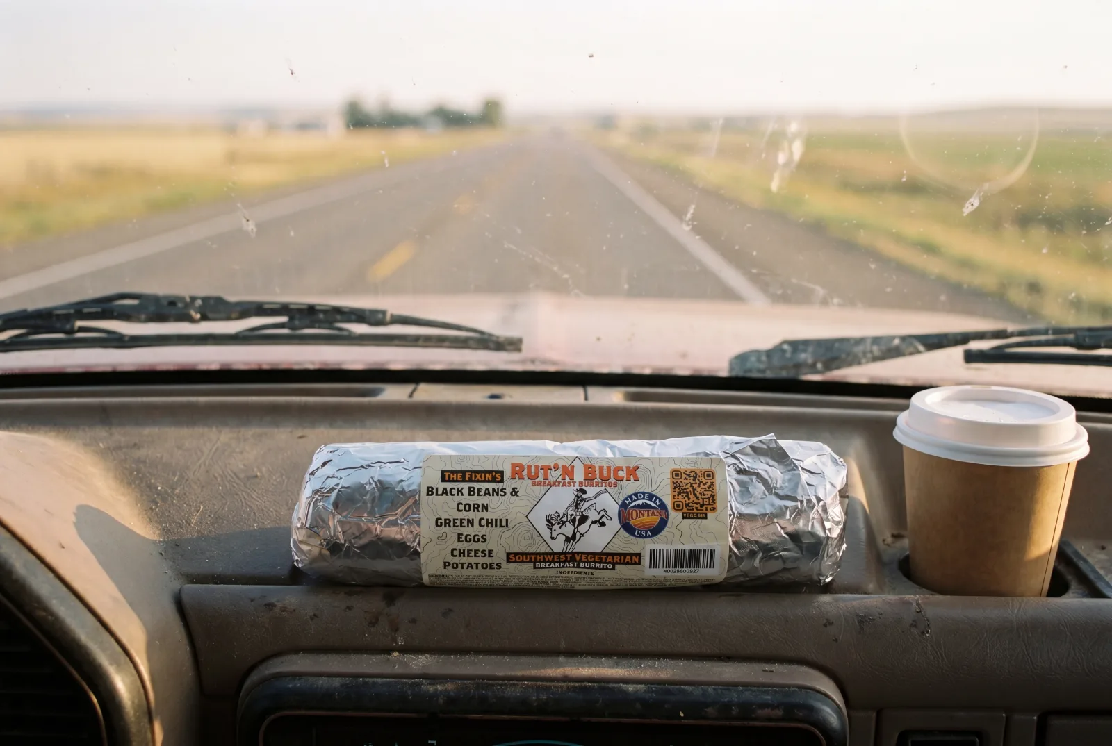 A breakfast burrito resting on a truck dashboard cupholder on the morning drive