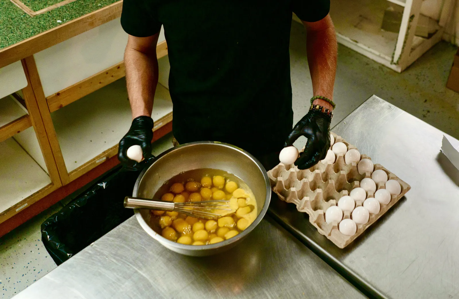 Carson cracking fresh eggs into a steel bowl in the kitchen