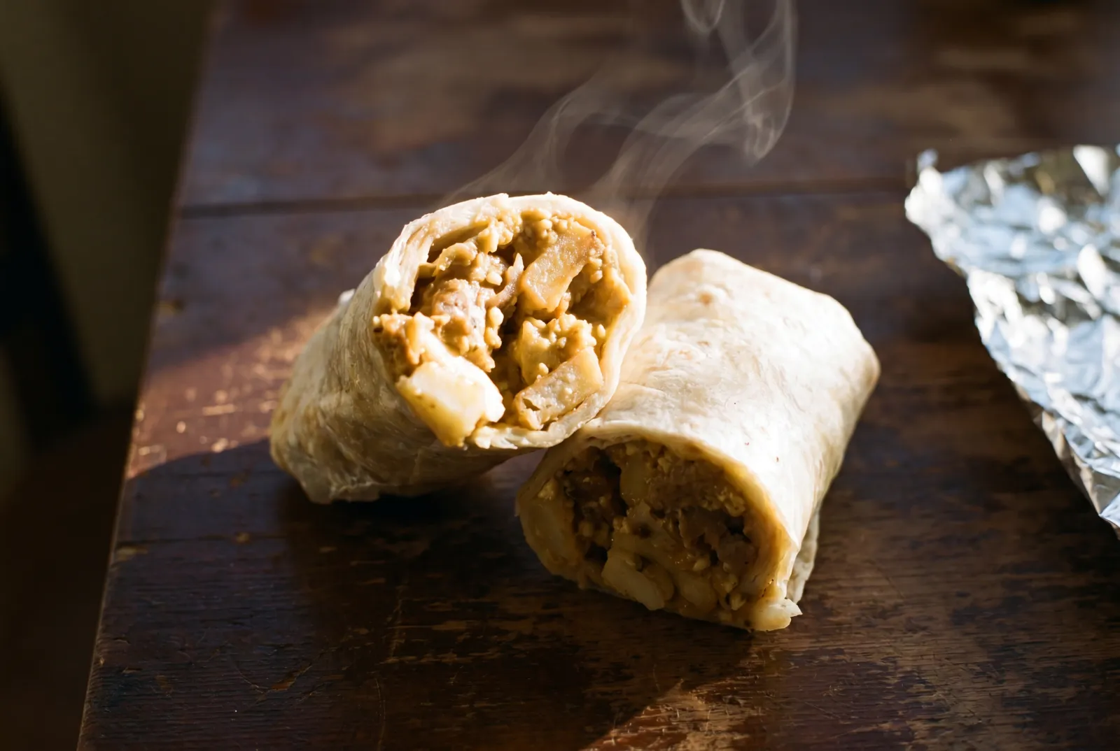 A Rut'n Buck breakfast burrito cross-section, steam rising, filling exposed
